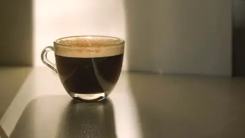 Una taza de café en una mesa con luz de ventana