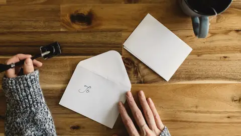 Unas manos escribiendo una tarjeta sobre una mesa de madera