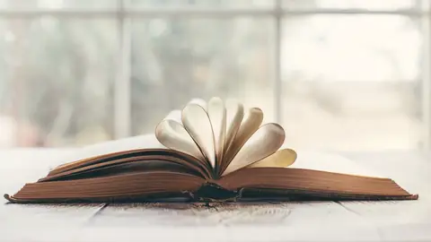 Un libro abierto junto a una ventana