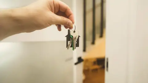 Una mano sujeta unas llaves junto a una puerta abierta