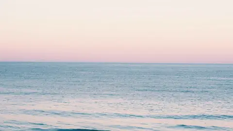 El mar en calma bajo un cielo rosado