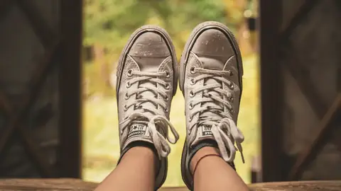 Unos pies con zapatillas frente a una puerta abierta al jardín