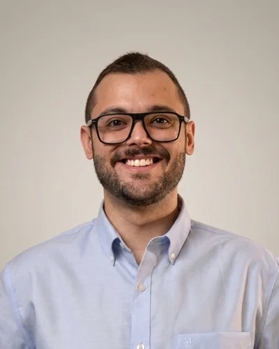 Adrián Cuñat Andrés, de frente, con camisa azul claro y gafas de pasta, sonriendo